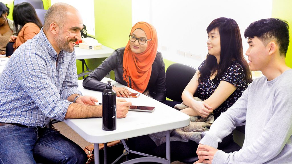 Professor Ahmed Allahwala with three students in a seminar, University of Toronto Scarborough